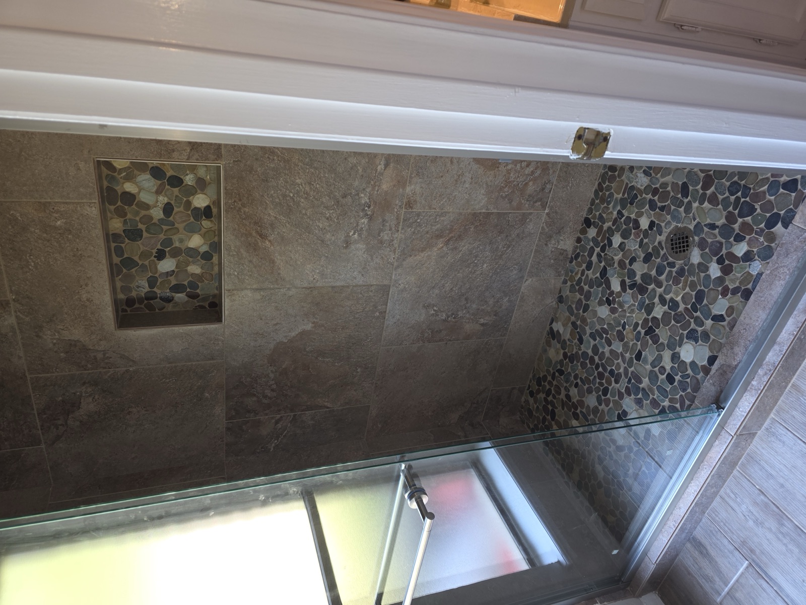 Walk-in shower with pebble mosaic floor and glass panel