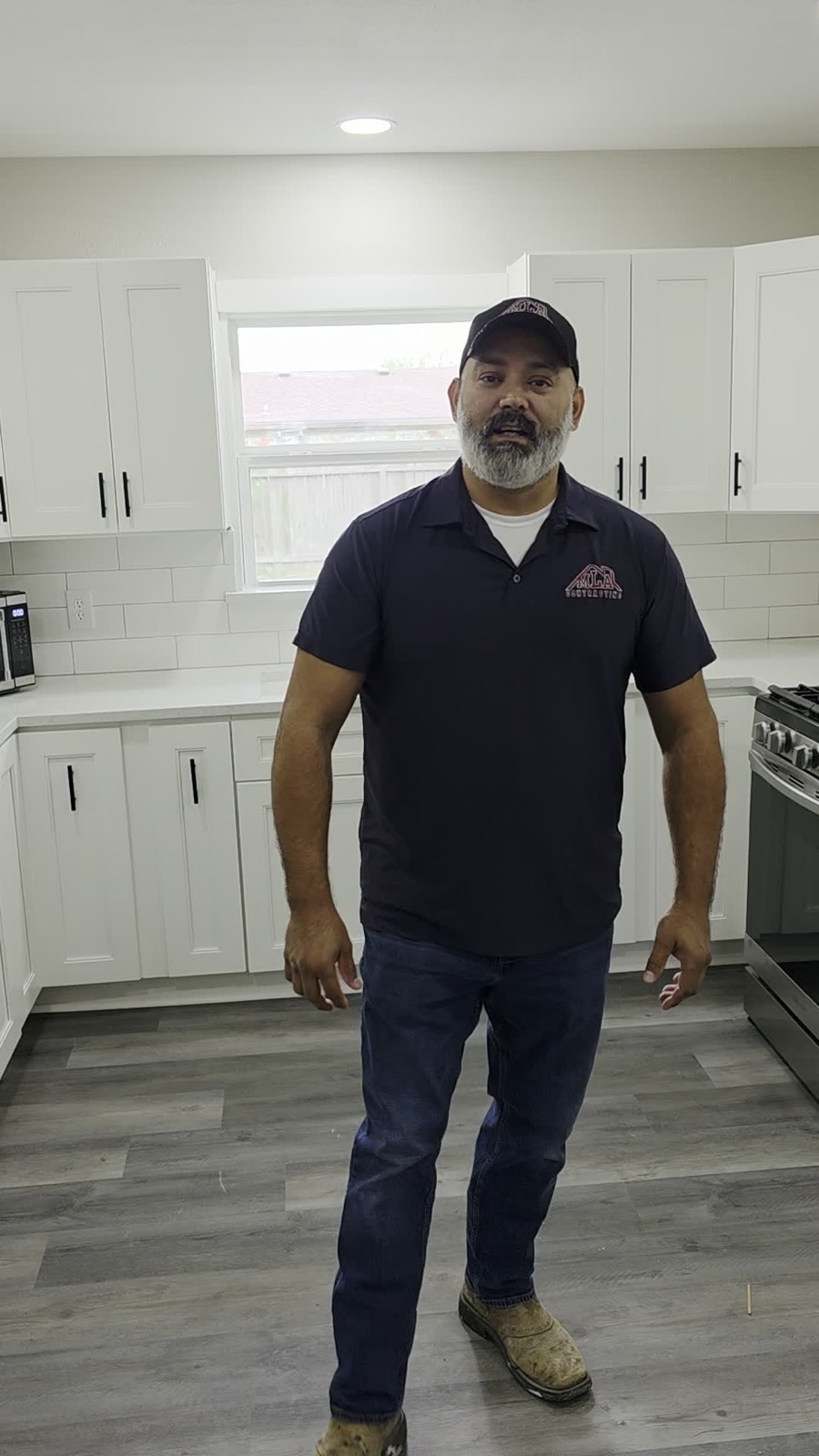Juan Martinez, owner of MLA Contracting, standing in a finished white kitchen remodel