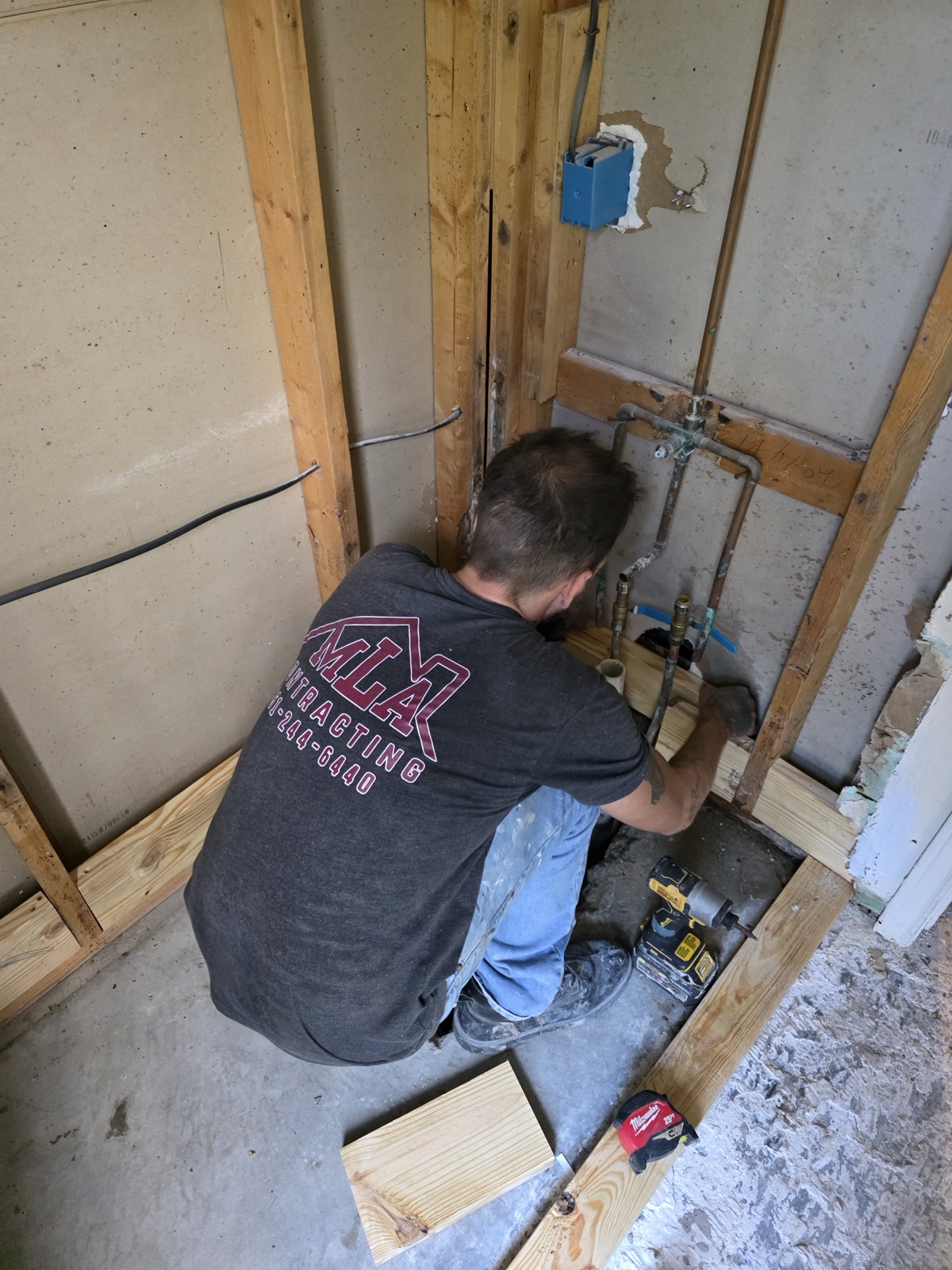 MLA Contracting crew member in branded shirt working a bathroom rough-in