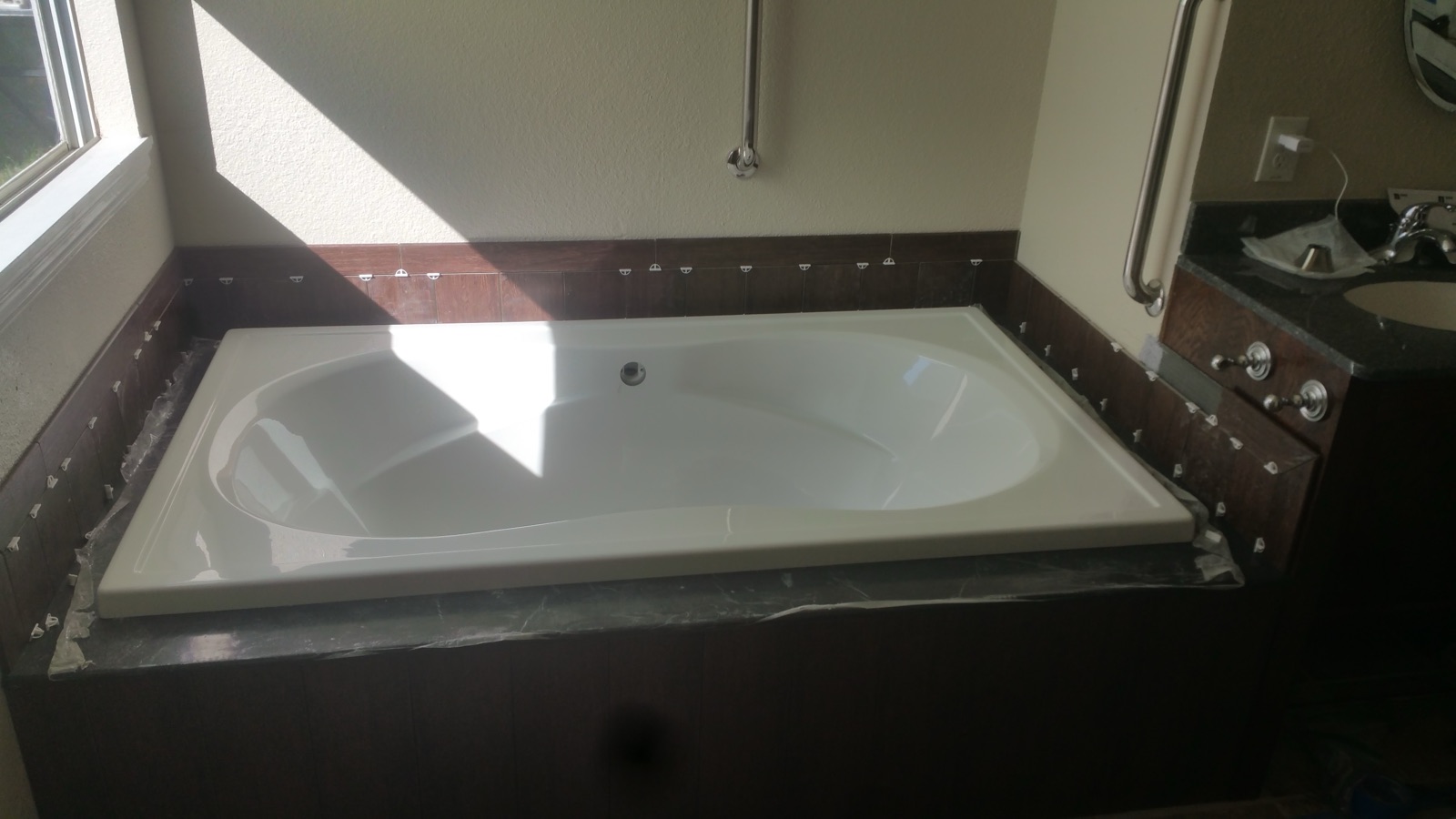 Drop-in soaking tub with dark wood surround